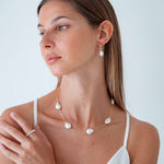 Woman wearing a necklace and earrings with a plain background