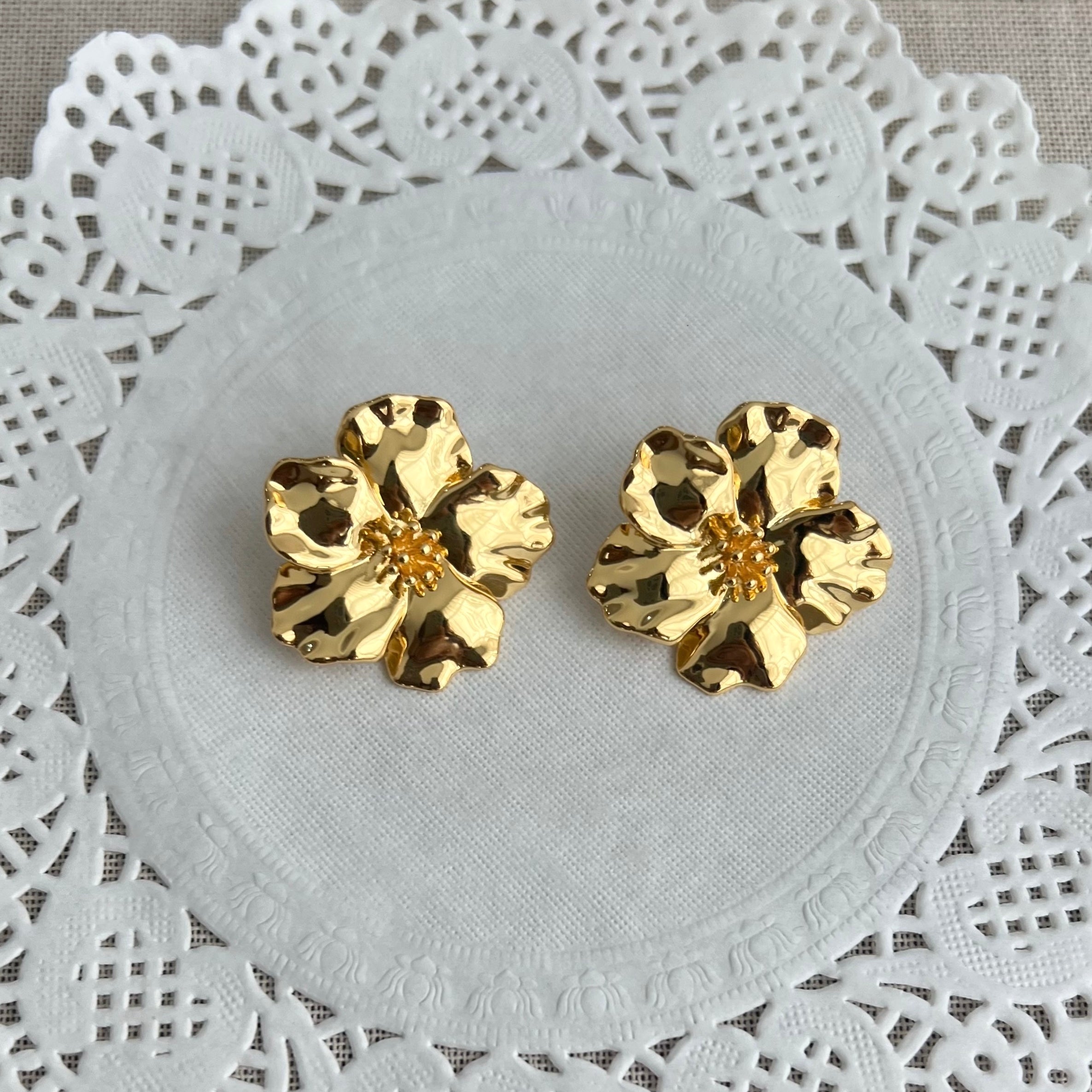 Gold floral earrings on a white dolly, flower earrings