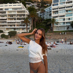 Woman on a beach with a mountain and buildings in the background in cape town south africa and waering gold bangles 