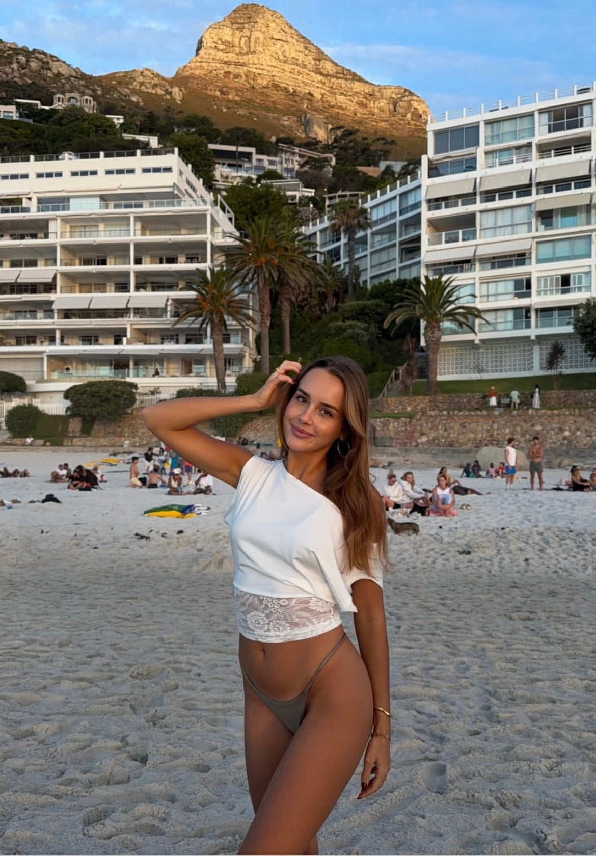 Woman on a beach with a mountain and buildings in the background in cape town south africa and waering gold bangles 