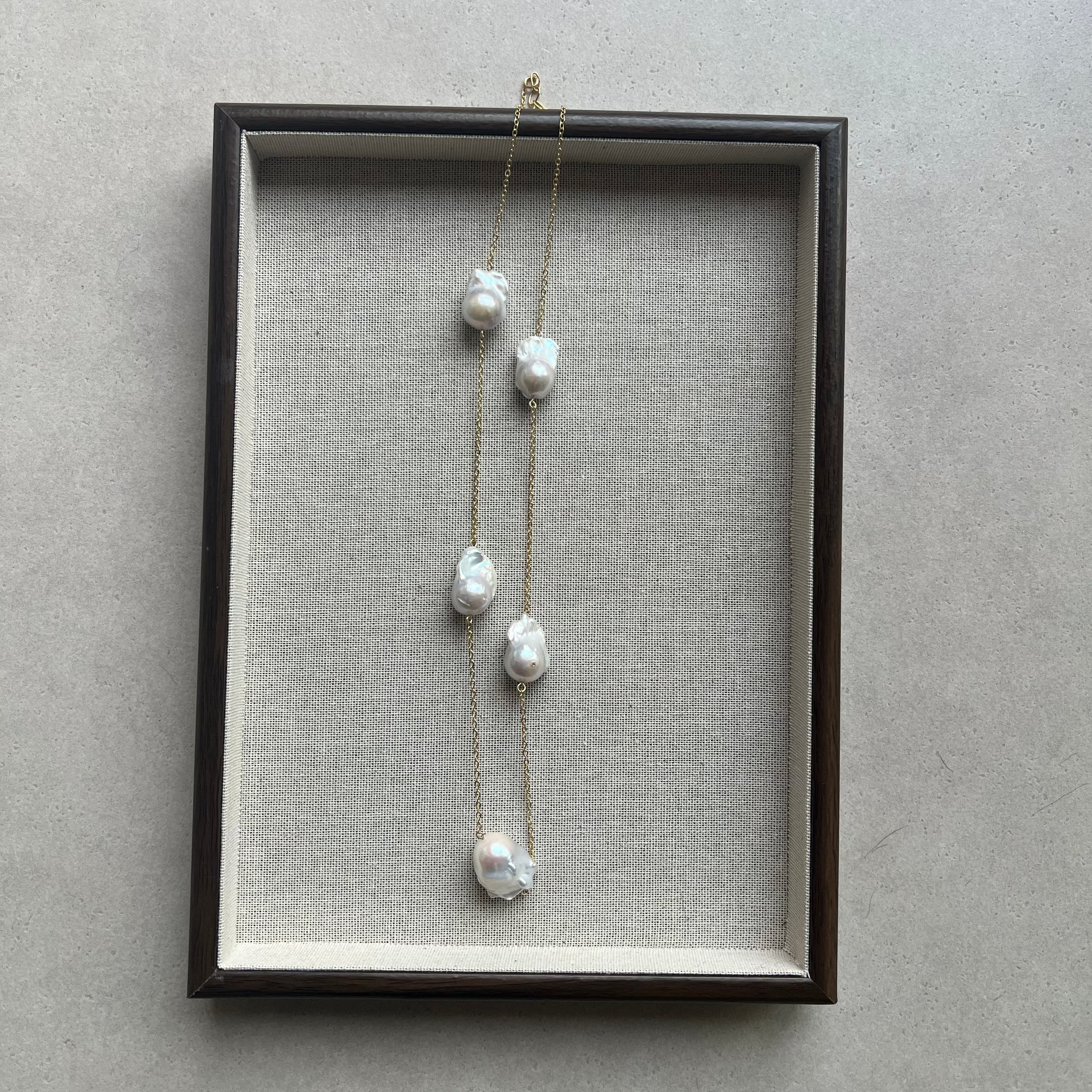 Pearl necklace in a black frame on a gray background