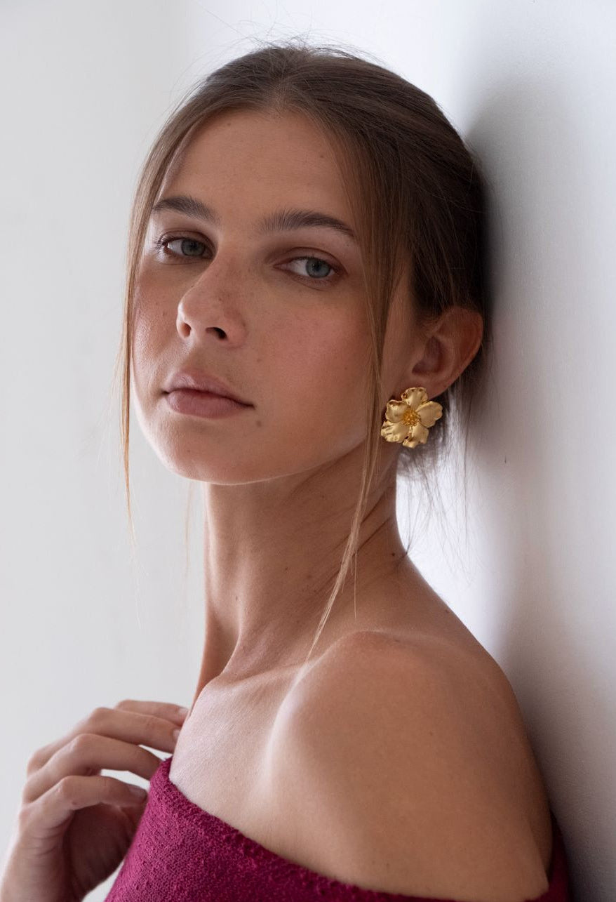 Woman wearing gold earrings against a white wall